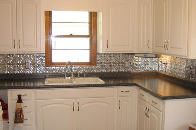 Example of a mid-sized eclectic l-shaped eat-in kitchen design in Minneapolis with a drop-in sink, raised-panel cabinets, white cabinets, laminate countertops, metal backsplash, stainless steel appliances and no island