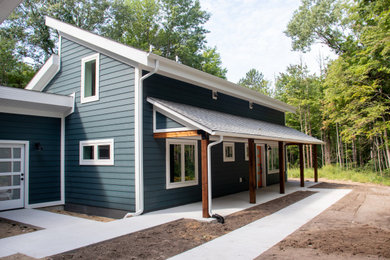 Example of a mid-sized minimalist blue split-level vinyl and clapboard house exterior design in Grand Rapids with a shed roof, a shingle roof and a black roof