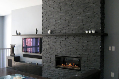 Modelo de sala de estar abierta moderna de tamaño medio con paredes púrpuras, suelo de madera oscura, todas las chimeneas, marco de chimenea de piedra y televisor colgado en la pared