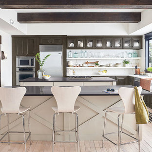 Design ideas for a large modern l-shaped eat-in kitchen in Houston with a double-bowl sink, raised-panel cabinets, dark wood cabinets, quartz benchtops, white splashback, marble splashback, stainless steel appliances, light hardwood floors, multiple islands, pink floor and black benchtop.
