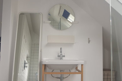 This is an example of a large contemporary wet room bathroom in London with a wall mounted toilet, white walls, ceramic flooring, a pedestal sink, grey floors and an open shower.