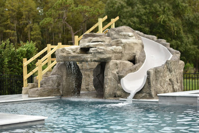 Example of a large trendy backyard stone and custom-shaped water slide design in Tampa