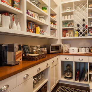 Cette photo montre une grande arrière-cuisine chic en L avec un placard avec porte à panneau encastré, des portes de placard blanches, un plan de travail en bois, une crédence blanche, une crédence en carreau de céramique, un électroménager encastrable et un sol en bois foncé.