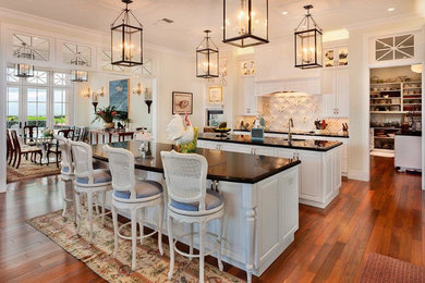 Eat-in kitchen - large traditional single-wall dark wood floor and brown floor eat-in kitchen idea in San Diego with an undermount sink, raised-panel cabinets, white cabinets, quartz countertops, white backsplash and two islands