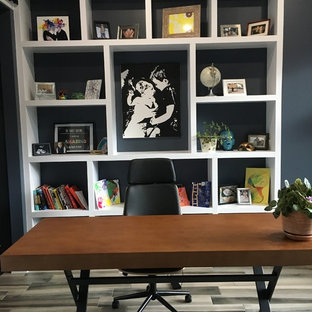 Large modern home office and library in Edmonton with a reading nook, blue walls, ceramic flooring, a freestanding desk and grey floors.