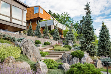 This is an example of an expansive contemporary sloped partial sun xeriscape for summer in Denver with a garden path and natural stone pavers.