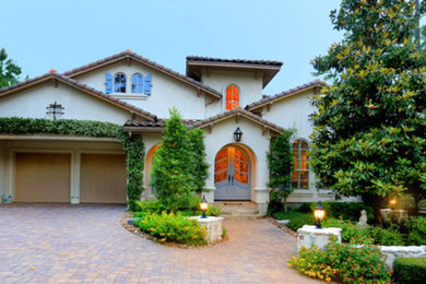 Design ideas for a large mediterranean two-storey stucco beige exterior in Houston.