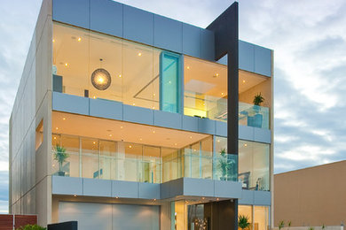 This is an example of a contemporary three-storey house exterior in Adelaide with metal siding and a flat roof.