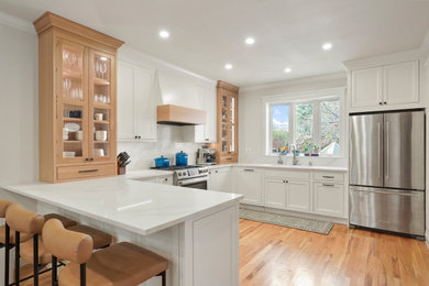 Inspiration for a large transitional u-shaped eat-in kitchen remodel in Denver with an undermount sink, shaker cabinets, white cabinets, quartz countertops, white backsplash, quartz backsplash, stainless steel appliances, a peninsula and white countertops