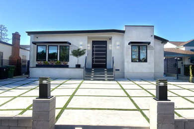 Mid-sized minimalist gray stucco house exterior photo in Los Angeles with a black roof
