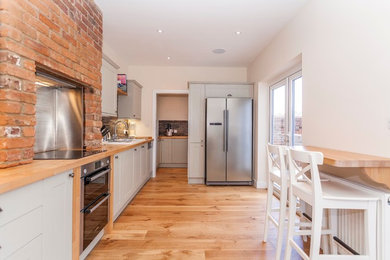 This is an example of a contemporary single-wall kitchen in Hampshire with brown splashback, stone tiled splashback, stainless steel appliances and medium hardwood flooring.