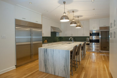 Large trendy u-shaped light wood floor eat-in kitchen photo in Philadelphia with an undermount sink, flat-panel cabinets, white cabinets, granite countertops, black backsplash, stone slab backsplash, stainless steel appliances and an island
