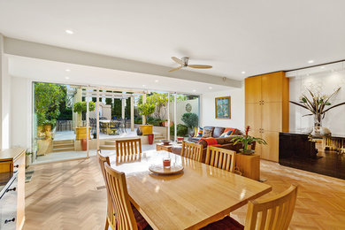 Photo of a mid-sized contemporary open concept living room in Melbourne with white walls and light hardwood floors.