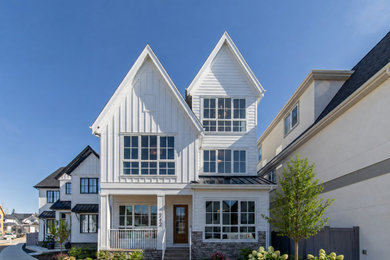 Mid-sized country white three-story mixed siding and board and batten exterior home photo with a shingle roof and a black roof