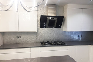 Design ideas for a large modern eat-in kitchen in Hertfordshire with flat-panel cabinets, white cabinets, marble benchtops, grey splashback, glass sheet splashback and no island.