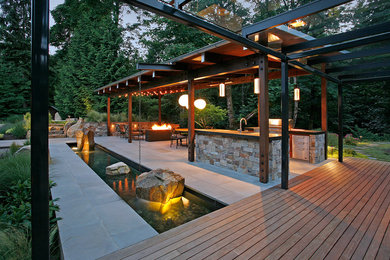 Photo of a country backyard patio in Seattle with a fire feature and concrete pavers.