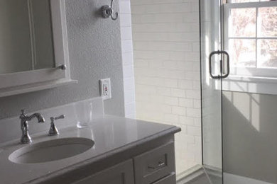 Inspiration for a mid-sized transitional 3/4 black and white tile and subway tile mosaic tile floor and multicolored floor alcove shower remodel in Other with shaker cabinets, gray cabinets, beige walls, an undermount sink, quartz countertops and a hinged shower door