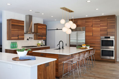 Inspiration for a contemporary u-shaped medium tone wood floor and brown floor open concept kitchen remodel in Grand Rapids with an undermount sink, flat-panel cabinets, dark wood cabinets, marble countertops, white backsplash, stone slab backsplash, stainless steel appliances, an island and white countertops