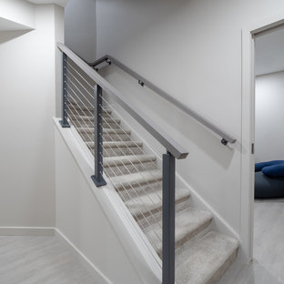 Photo of an expansive contemporary walk-out basement in Other with grey walls, laminate floors, no fireplace and grey floors.