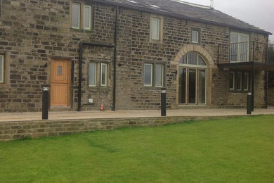 This is an example of a gey rural house exterior in Other with stone cladding and a tiled roof.
