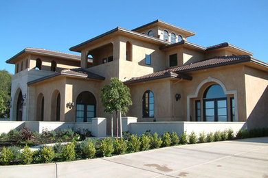 Large mediterranean three-storey beige house exterior in Sacramento with stone veneer, a gable roof and a tile roof.