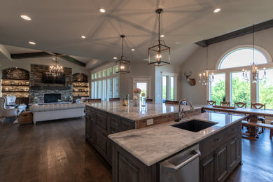Example of a large mountain style l-shaped dark wood floor, brown floor and vaulted ceiling kitchen pantry design in Kansas City with shaker cabinets, two islands, marble countertops, multicolored countertops, gray cabinets, brown backsplash, brick backsplash, an undermount sink and stainless steel appliances