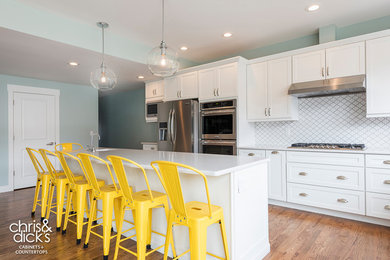 Kitchen pantry - large transitional l-shaped light wood floor kitchen pantry idea in Salt Lake City with shaker cabinets, white cabinets, quartzite countertops, white backsplash, ceramic backsplash, stainless steel appliances, an island and an undermount sink