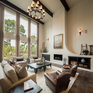 Repräsentatives, Fernseherloses, Offenes Mediterranes Wohnzimmer mit weißer Wandfarbe, dunklem Holzboden, Kamin, Kaminsims aus Metall und braunem Boden in Austin