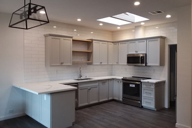 Mid-sized transitional u-shaped ceramic tile and black floor eat-in kitchen photo in Phoenix with an undermount sink, flat-panel cabinets, gray cabinets, quartz countertops, white backsplash, subway tile backsplash, stainless steel appliances, a peninsula and white countertops