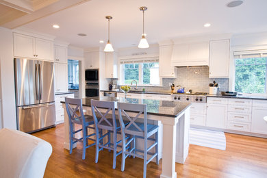 Enclosed kitchen - large coastal u-shaped medium tone wood floor enclosed kitchen idea in Boston with an undermount sink, shaker cabinets, white cabinets, granite countertops, gray backsplash, subway tile backsplash, stainless steel appliances and an island