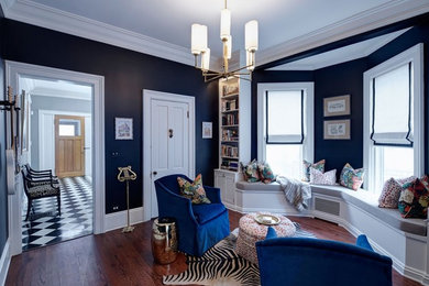 Example of a mid-sized classic enclosed medium tone wood floor and brown floor family room design in Chicago with black walls and no fireplace