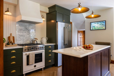 Example of a classic light wood floor kitchen design in Boston with a farmhouse sink, shaker cabinets, green cabinets, marble countertops, white backsplash, marble backsplash, stainless steel appliances, an island and white countertops