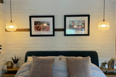 ハートフォードシャーにある小さなコンテンポラリースタイルのおしゃれな主寝室 (ベージュの壁、濃色無垢フローリング、標準型暖炉、レンガの暖炉まわり、茶色い床、表し梁、レンガ壁、照明) のレイアウト