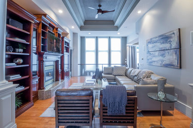 Example of a mid-sized classic enclosed medium tone wood floor family room design in Edmonton with gray walls, a standard fireplace, a tile fireplace and a wall-mounted tv