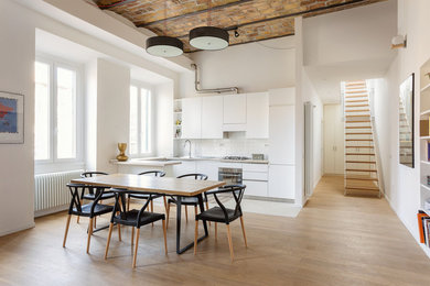 This is an example of a mid-sized contemporary u-shaped eat-in kitchen in Rome with flat-panel cabinets, white cabinets, white splashback, subway tile splashback, a peninsula, panelled appliances, light hardwood floors and brown floor.