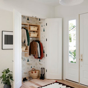 ミネアポリスの片開きドアエクレクティックスタイルのおしゃれな玄関ロビー (白い壁、淡色無垢フローリング、白いドア、ベージュの床) の写真