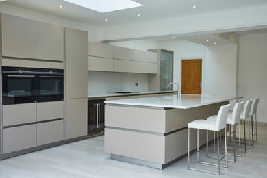 This is an example of a large modern single-wall kitchen/diner in Essex with a built-in sink, flat-panel cabinets, beige cabinets, quartz worktops, white splashback, integrated appliances, ceramic flooring, an island, beige floors and white worktops.