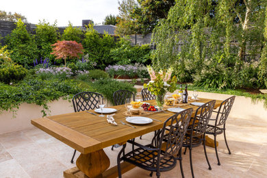 Photo of a small backyard partial sun garden for fall in Melbourne with natural stone pavers, a wood fence and a retaining wall.