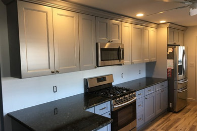 Mid-sized trendy u-shaped vinyl floor eat-in kitchen photo in New York with a single-bowl sink, recessed-panel cabinets, blue cabinets, granite countertops, stainless steel appliances and no island