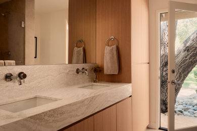 Example of a mid-sized trendy beige tile and porcelain tile porcelain tile, gray floor and double-sink bathroom design in Los Angeles with flat-panel cabinets, light wood cabinets, a one-piece toilet, white walls, an undermount sink, quartz countertops, a hinged shower door, beige countertops and a built-in vanity