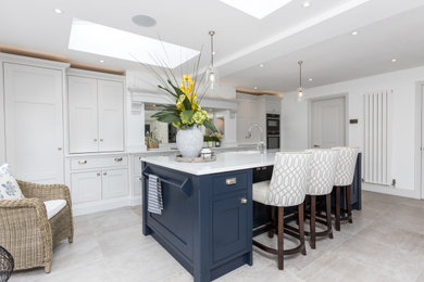 Photo of a classic kitchen in Berkshire with a belfast sink, shaker cabinets, engineered stone countertops, mirror splashback, an island and white worktops.