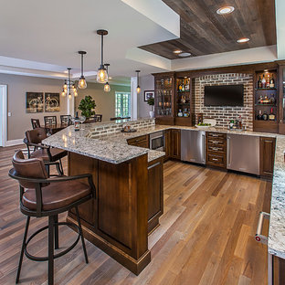Inspiration for an expansive classic walk-out basement in Detroit with medium hardwood flooring, a standard fireplace, a brick fireplace surround and grey floors.