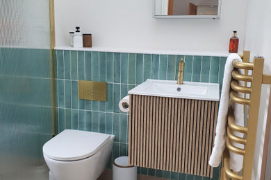 Design ideas for a medium sized contemporary shower room bathroom in Wiltshire with raised-panel cabinets, light wood cabinets, a walk-in shower, a wall mounted toilet, blue tiles, ceramic tiles, white walls, ceramic flooring, a wall-mounted sink, solid surface worktops, beige floors, an open shower, white worktops, a single sink and a floating vanity unit.