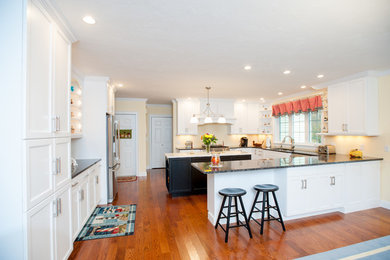 Mid-sized elegant u-shaped medium tone wood floor and brown floor eat-in kitchen photo in Boston with an undermount sink, shaker cabinets, white cabinets, granite countertops, stainless steel appliances and two islands