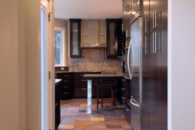 Mid-sized minimalist u-shaped slate floor enclosed kitchen photo in Austin with flat-panel cabinets, dark wood cabinets, solid surface countertops, stainless steel appliances and a peninsula