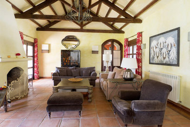 Modelo de salón cerrado de estilo de casa de campo grande con paredes verdes, suelo de baldosas de terracota, todas las chimeneas, televisor independiente y suelo marrón