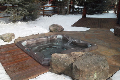 Hot tub - modern backyard stone and custom-shaped hot tub idea in Denver