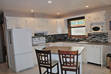 Example of a transitional l-shaped kitchen design in Other with white cabinets, laminate countertops, glass tile backsplash, white appliances and an island