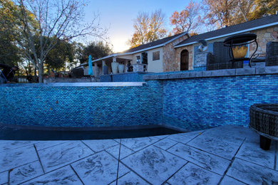 Diseño de piscina marinera extra grande redondeada en patio trasero con paisajismo de piscina y suelo de hormigón estampado