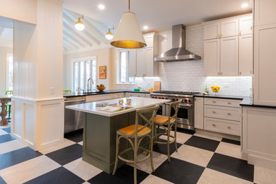 This is an example of a large traditional u-shaped eat-in kitchen in Philadelphia with an undermount sink, shaker cabinets, white cabinets, quartz benchtops, white splashback, ceramic splashback, stainless steel appliances, ceramic floors, with island, black floor and black benchtop.